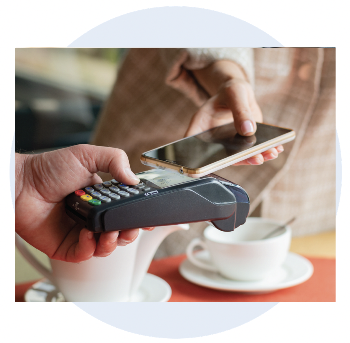 A customer pays for a coffee by tapping her phone on the shops card reader