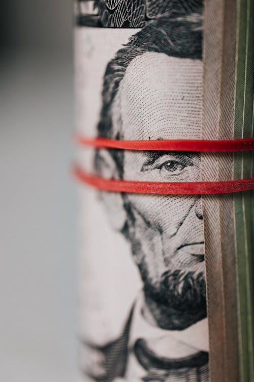 A stack of dollar bills is wrapped in a red rubber band. Abraham Lincoln, on the face of the $1 bill, is shown. payouts issues online have complicated cashflow for adult content creators.